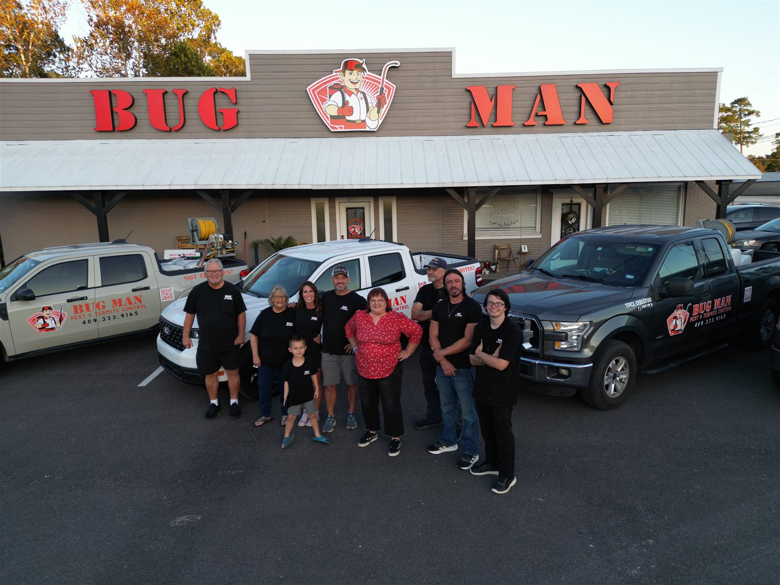 BugMan team standing beside service vehicles outside the BugMan office